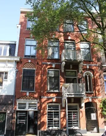 Voorgevel van een klassiek rood bakstenen woonhuis aan de Graaf Florisstraat met hoge ramen, twee balkons en fietsen voor de deur.